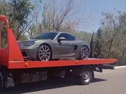 Auto deportivo gris de dos plazas sobre la plataforma de una grúa
