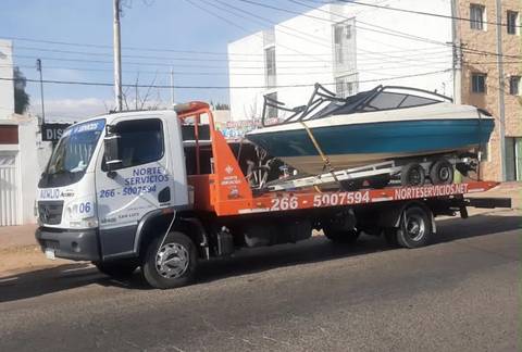 Lancha con su trailer cargada sobre la plataforma de una grúa, en la calle