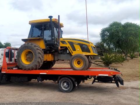 Tractor agrícola amarillo sobre la plataforma de una grúa